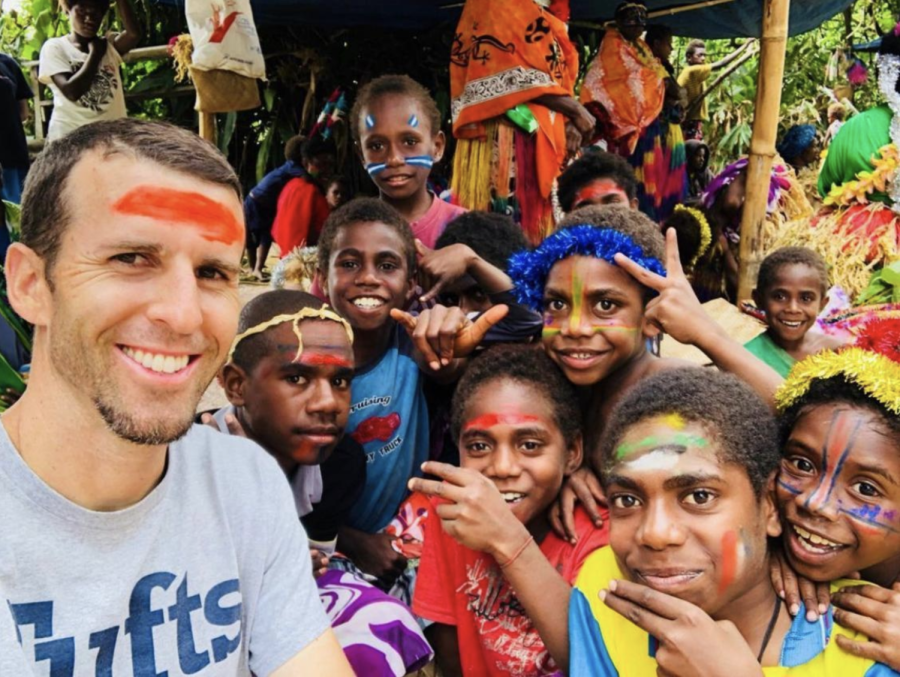 Brian Asher takes selfie with children in country that he visited.