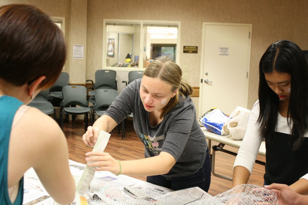 Blythe Newton-Haynes, Bella Nedich, and Katherine Ly prepare newspaper to create decorations